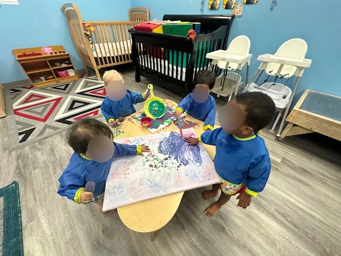 Children making a large blue painting together at Village Scholars Preschool